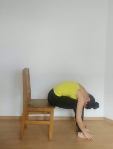 Image of a woman doing the forward fold on a chair