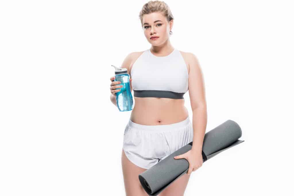 Image of a women holding a water bottle and a yoga mat