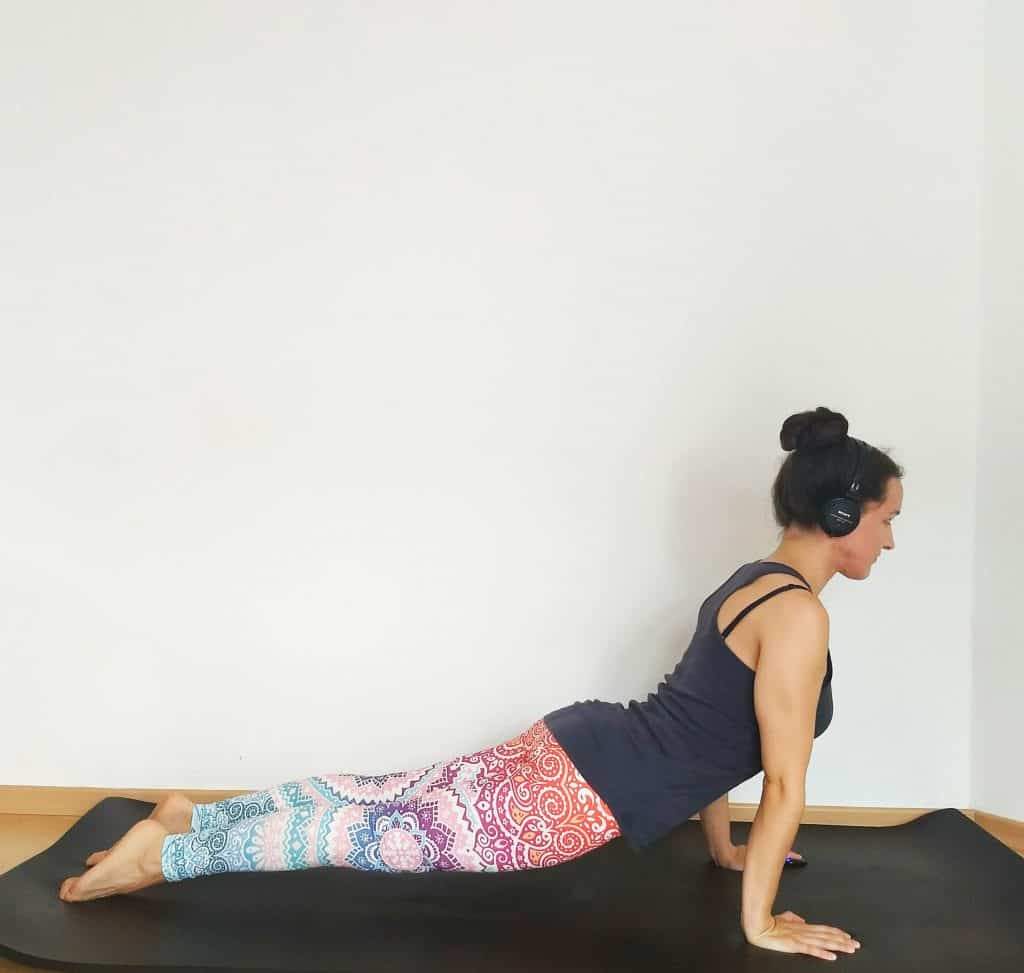 image of a woman in upward facing dog pose wearing headphones listening to yoga music