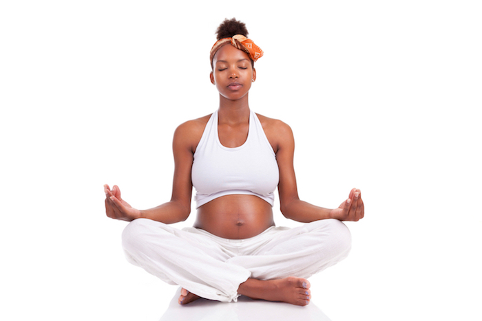 Image of a pregnant woman meditating in a cross-legged position