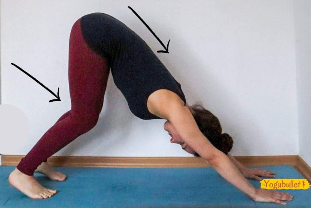 Image of a woman in downward facing dog position, working on straightening her back with her knees bent