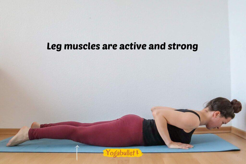 Image of a woman laying flat on her belly, her hand next to her chest and the leg muscles activating so that the knees are slightly lifting off the floor